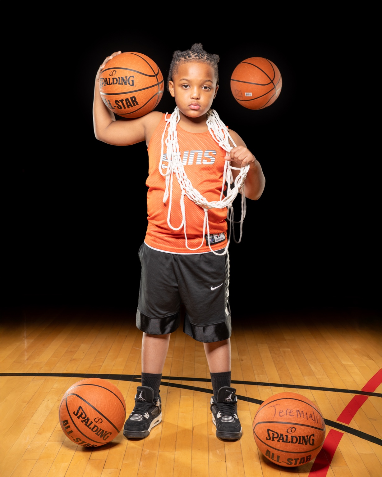 Young basketball athlete posing with ball and net.