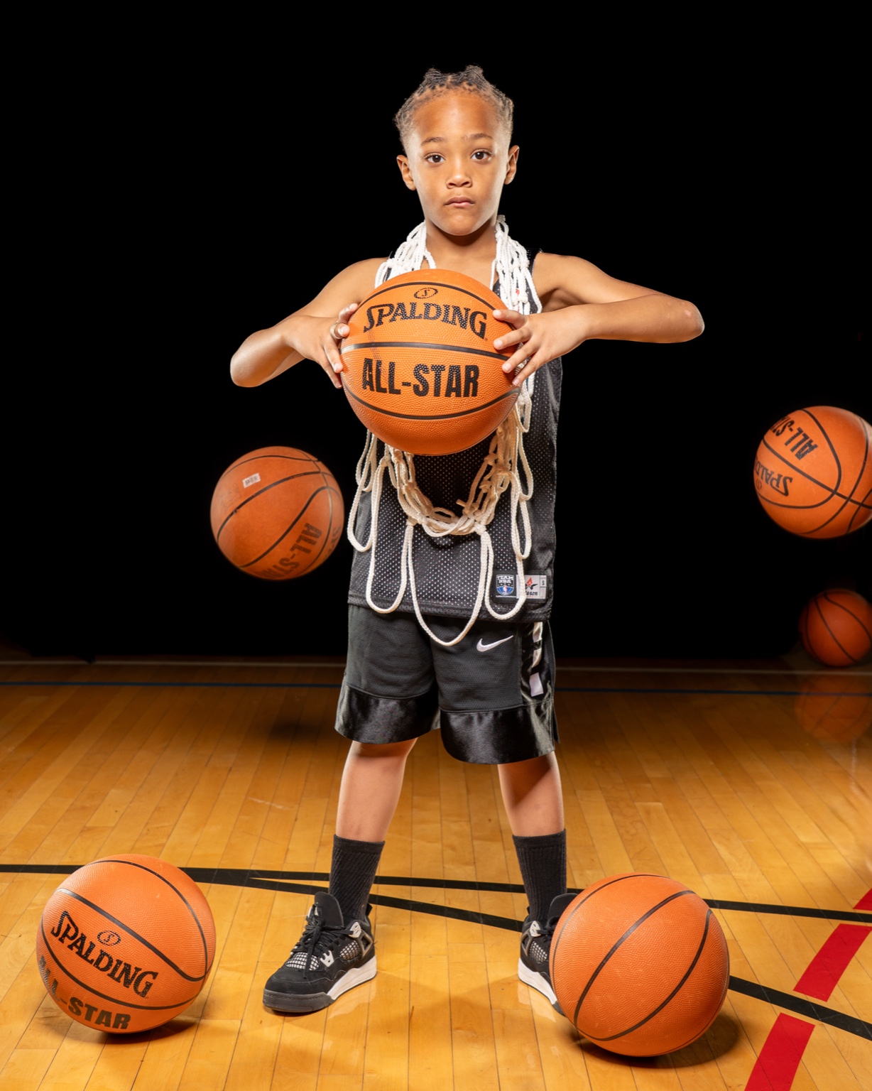Young athlete holding basketball with net around shoulders.